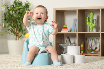 Little child sitting on plastic baby potty indoors. Space for text