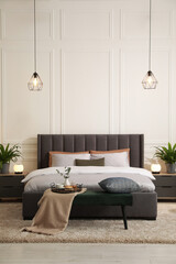 Stylish bedroom interior with large comfortable bed and ottoman