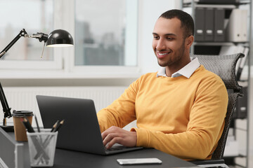 Young man working on laptop at table in office