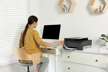 Woman using modern printer at workplace indoors