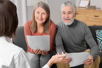 Insurance agent consulting elderly couple about pension plan in room - obrazy, fototapety, plakaty