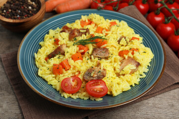 Delicious pilaf with meat and vegetables on wooden table, closeup