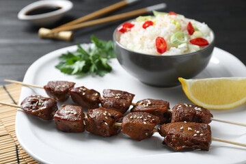 Tasty chicken meat glazed in soy sauce served with rice on black table, closeup