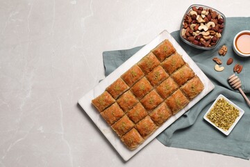Delicious sweet baklava with ingredients on light grey marble table, flat lay. Space for text
