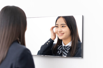 鏡を見ている日本人女子高校生/髪を耳にかけている