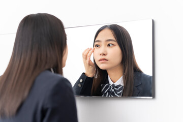 鏡を見ている日本人女子高校生/コンタクトを装着している