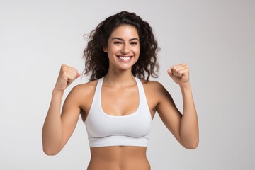 Fototapeta na wymiar Portrait of a smiling sportswoman in white sportswear showing her thumb up and her biceps isolated on a white background and Looking at the camera.