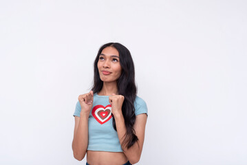 A young asian trans woman looking up celebrating in a subdued manner. Thankful and blissful for the success. Isolated on a white background.