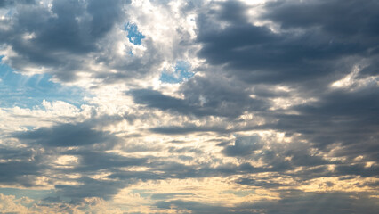 sunshine hide behind white and dark clouds on blue sky 