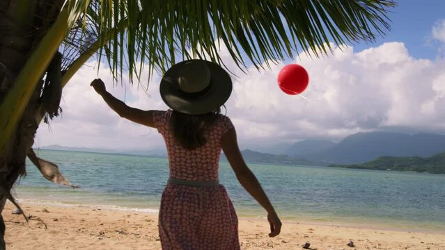 Woman Walking On Beach As Red Ballon Floats by