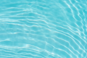 Blue water with ripples on the surface. Defocus blurred transparent blue colored clear calm water surface texture with splashes and bubbles. Water waves with shining pattern texture background.