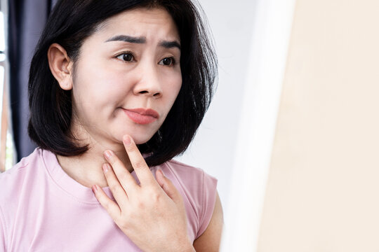 Asian woman having problem with Bell's Palsy,Facial Palsy, hand holding her face in front of a mirror