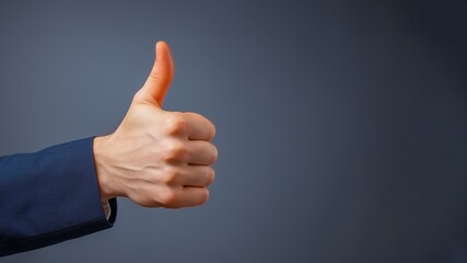 White-skinned hand in Jacket thumbs-up on a dark grey background
