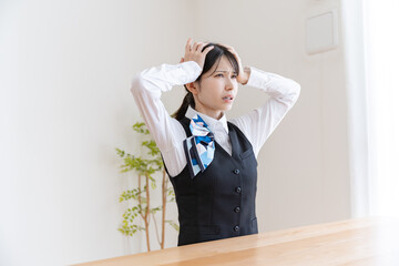 頭を抱える制服を着た日本人女性