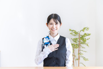 胸に手を当てる制服を着た日本人女性