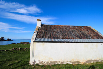 white scottish croft house cottage on an island in the sun with tin roof - obrazy, fototapety, plakaty