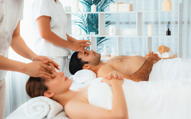 Obraz na płótnie Canvas Caucasian couple enjoying relaxing anti-stress head massage and pampering facial beauty skin recreation leisure in dayspa modern light ambient at luxury resort or hotel spa salon. Quiescent