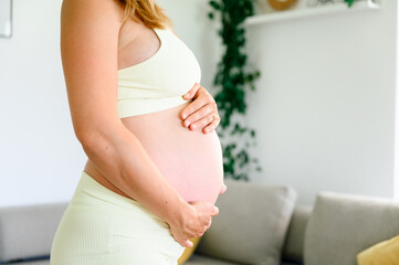 Crop unrecognizable pregnant woman holding belly with hands