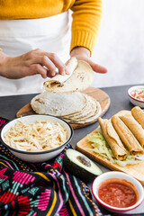 Mexican woman cooking tacos dorados called flautas with chicken, traditional fried food in Mexico Latin America