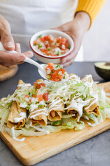 Mexican woman cooking tacos dorados called flautas with chicken, traditional fried food in Mexico...