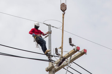 Electricians working on power pole connecting cables