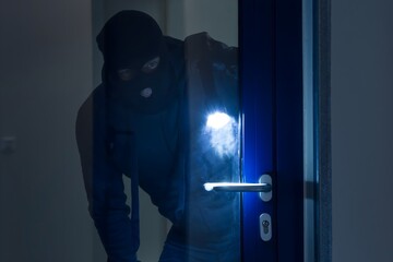 Thief With Flashlight Trying To Break Door