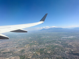Obraz premium White wing from airplane window over city. Great views of landscape. Aerial view city life through a plane window. Wing of airplane