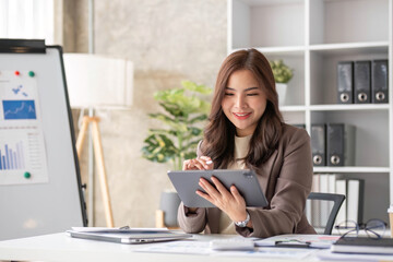 Cheerful business lady working on laptop in office, Asian happy beautiful businesswoman in formal suit work in workplace. Attractive female employee office worker smile.