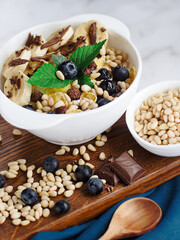 Useful breakfast. Fruit salad with banana, pine nuts, blueberries, chocolate and corn flakes. Fitness recipe for healthy balanced breakfast. Still life. Top view.