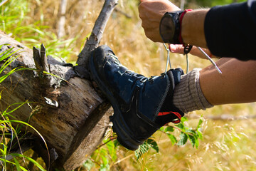 close-up of tying a mountain boot on a tree trunk. Mountain hiking