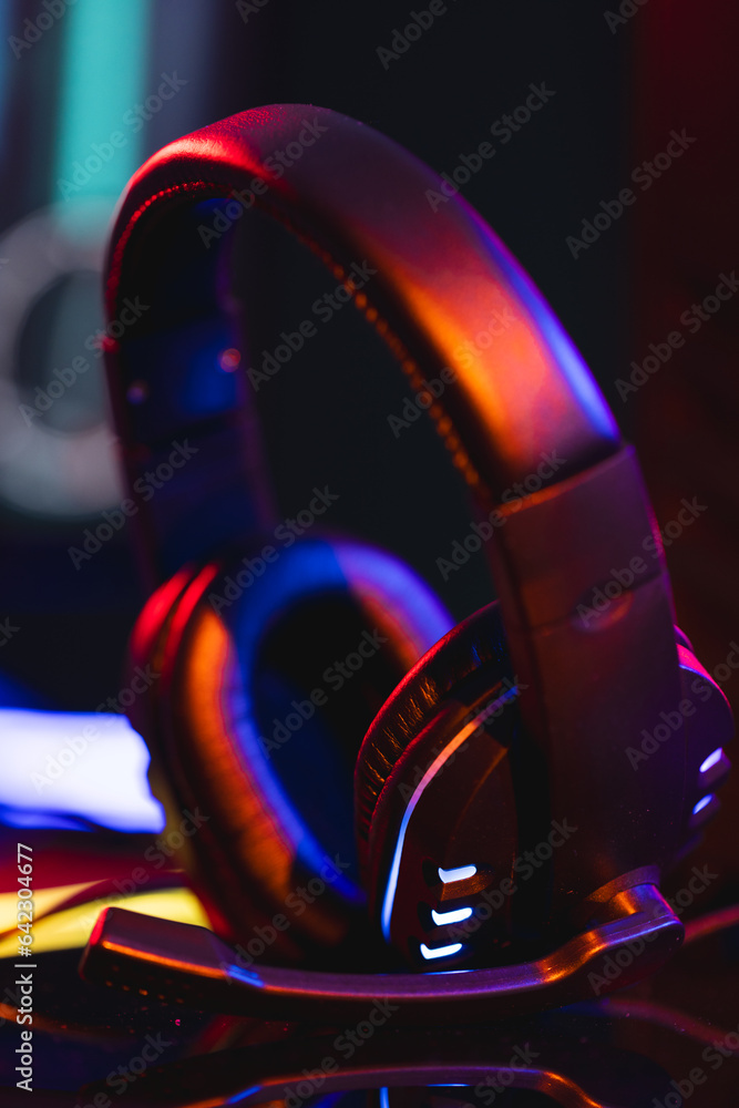 Poster vertical image of composite of video game headphones with copy space on neon background