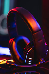 Vertical image of composite of video game headphones with copy space on neon background