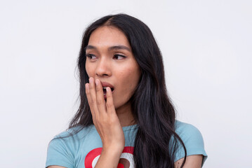 A young asian trans woman exclaiming gosh, covering her mouth in disbelief. Wearing a cute heart printed shirt. Isolated on a white background.