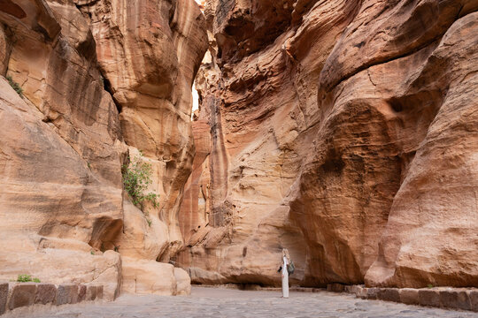 Blonde woman in The Siq, the way to Al Khazneh (The Treasury), ancient city of Petra, Jordan