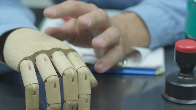 Close Up Arms Of Disabled Employee With Prosthetic Arm Doing Paperwork