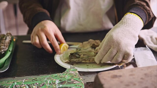 獲れたての牡蠣をカキ小屋で食べる女性
