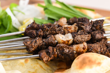 Swek of beef Tikka with bahraini bread tandoori nan, lime and salad served in dish isolated on wooden table top view middle eastern grills food