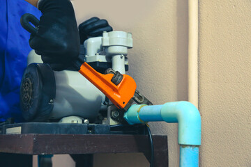 Technician plumber using a wrench to repair a water pump pipe. Concept of maintenance, fix water...
