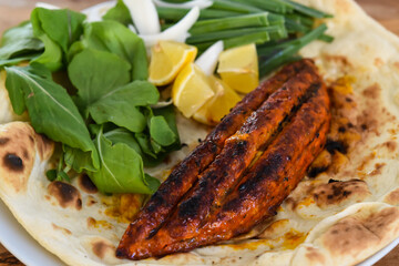 Chicken Stuffed With Cheese meat seekh kebab with bahraini bread tandoori nan, lime and salad served in dish isolated on wooden table top view middle eastern grills food