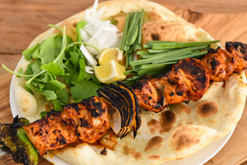 Shish Tawook kebab with bahraini bread tandoori nan, lime and salad served in dish isolated on wooden table top view middle eastern grills food
