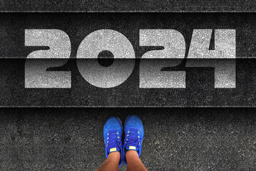 happy new year 2024. man legs in sneakers standing next to stairs with number 2024
