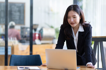 Businesswoman in office looking at laptop screen and showing excitement and joy about a successful business project.