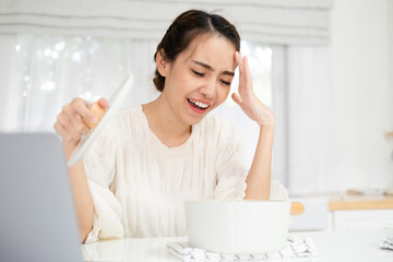 Dissatisfied asian Woman Cooking at home and Looking into Pot.