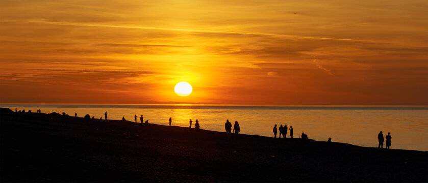 People on the seashore during the sunset.