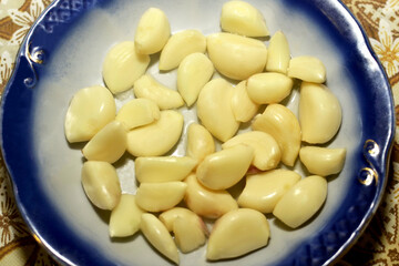 Peeled garlic cloves are in a plate close-up