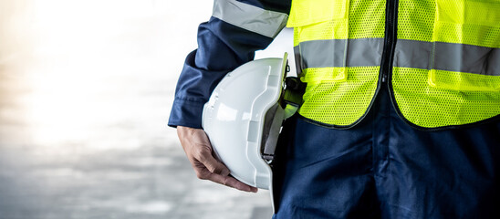 Safety workwear concept. Male hand holding white safety helmet or hard hat. Construction worker man...