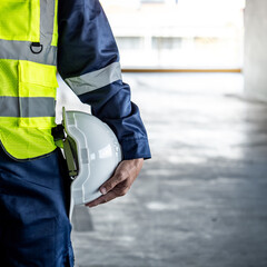 Safety workwear concept. Male hand holding white safety helmet or hard hat. Construction worker man...