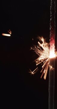 Vertical video of lit sparkler and copy space on black background