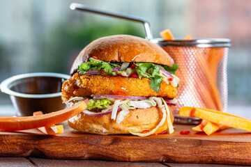 Hamburger with chicken cutlet, fresh tomatoes, red onion, lettuce and tomato sauce. Next to the...