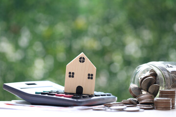 Finance, Model house on calculator and stack of coins money on natural green background,Business...